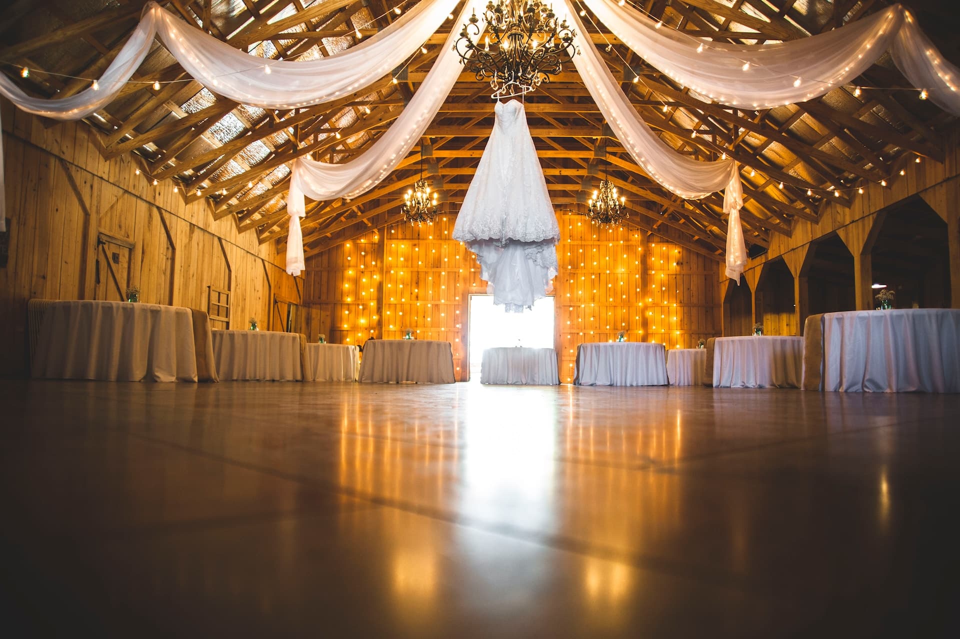 wedding venue in a barn with lights and drapes hanging from the ceiling
