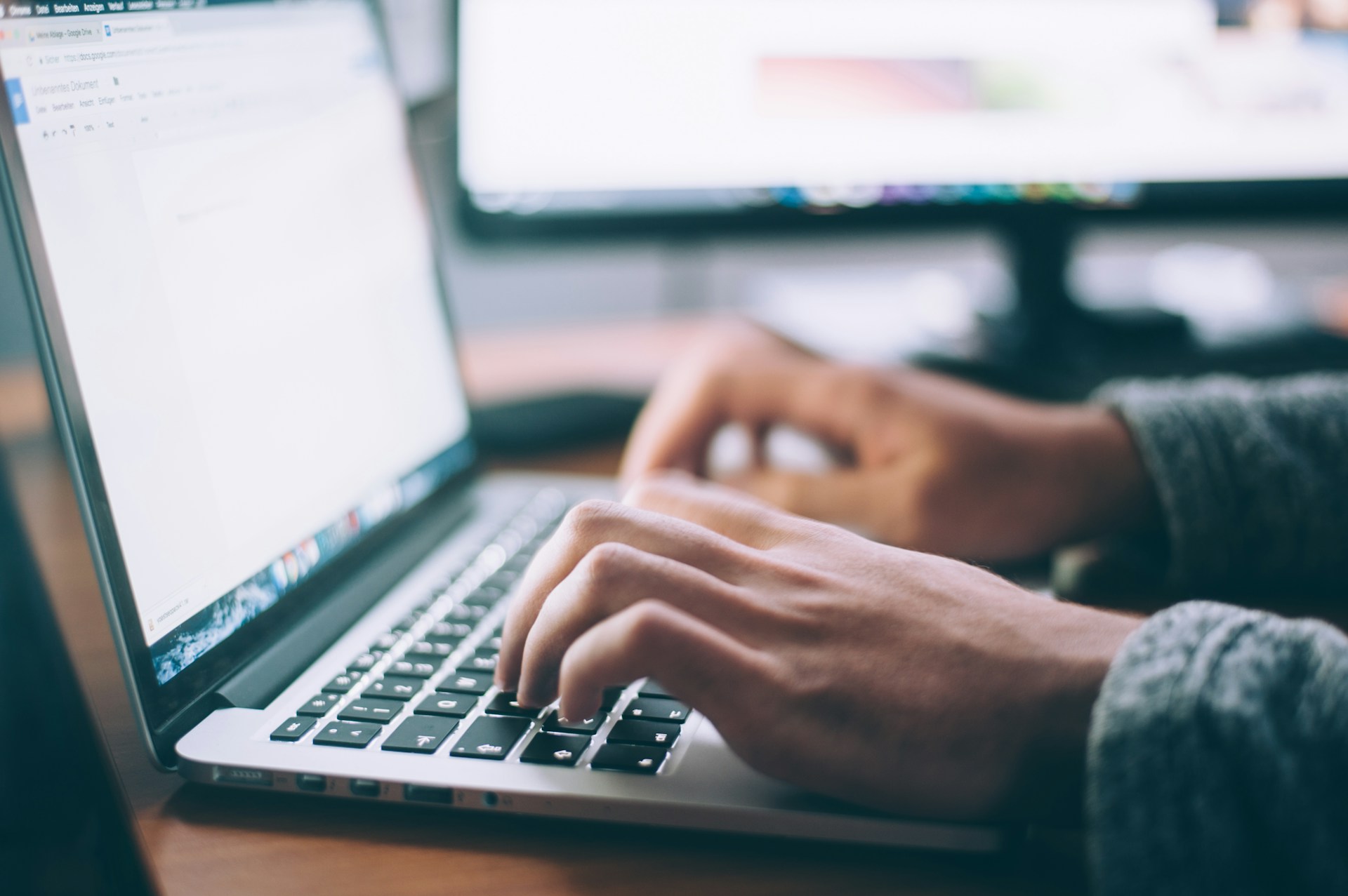 Hands typing on a laptop