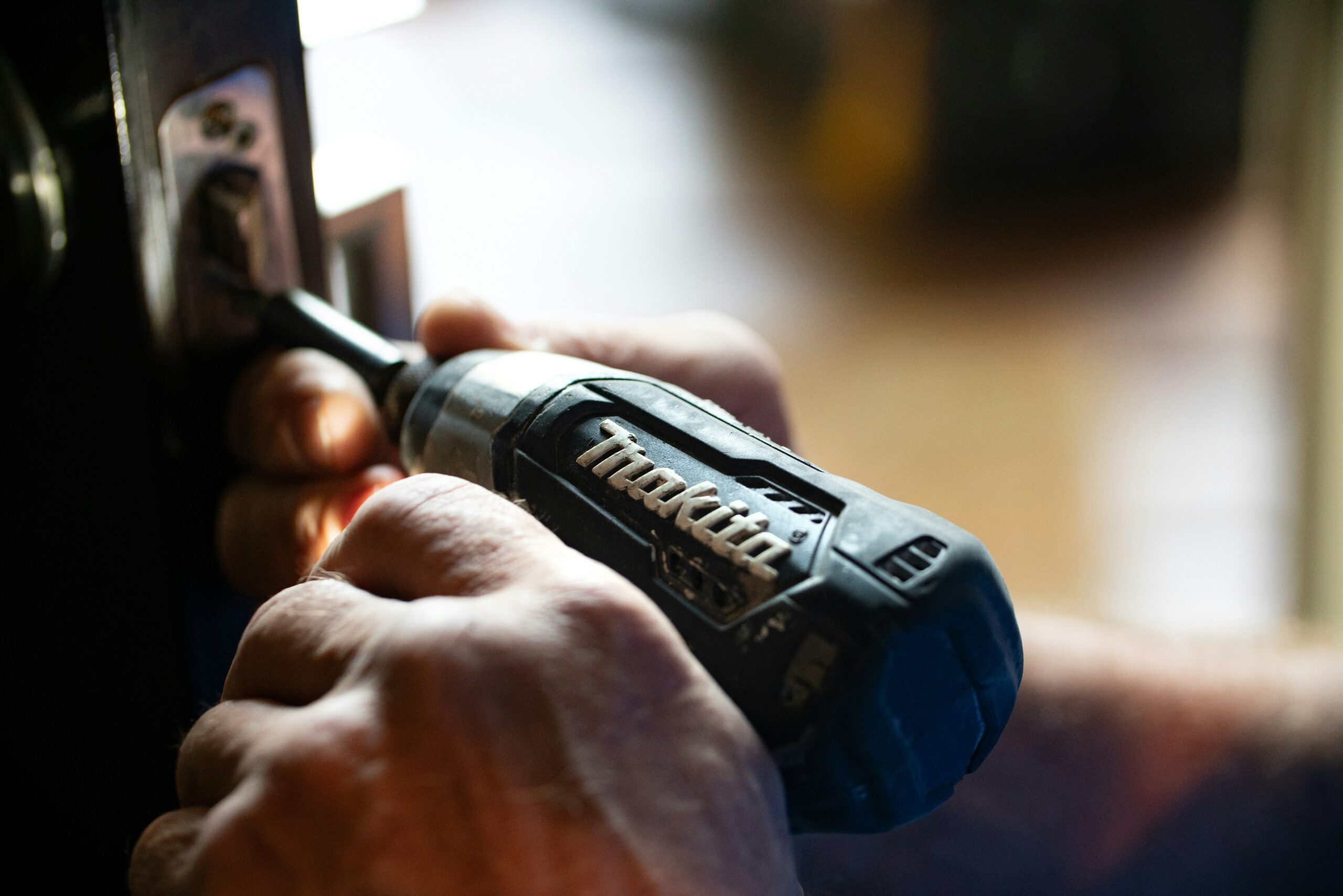 Man fixing a door with a power drill