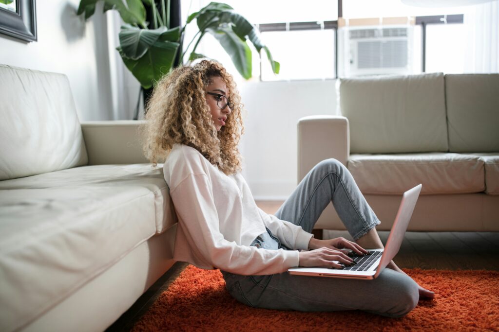 Woman working on a laptop while sitting on the floor