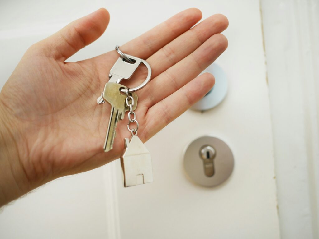 hand holding house key in front of a door