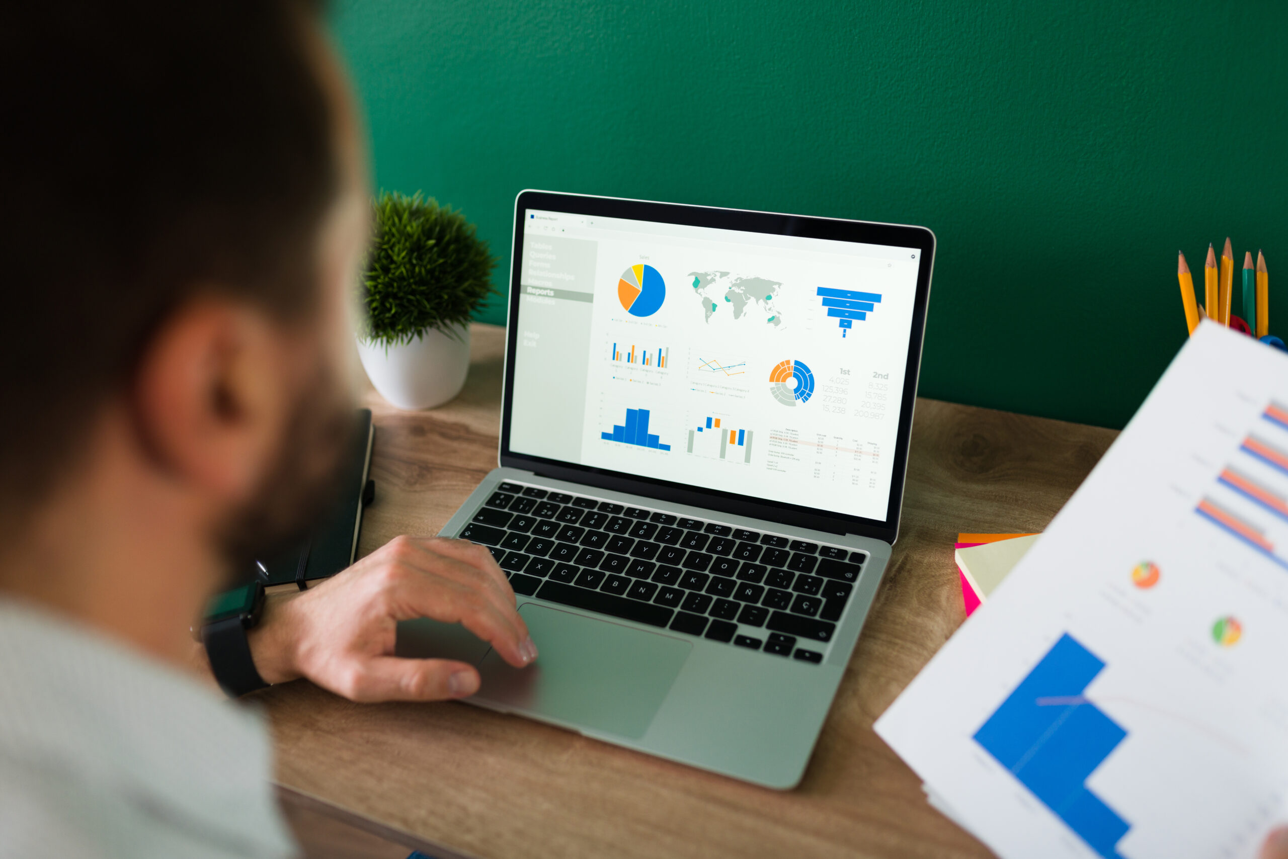 young man working on his laptop and looking at a report and graphs for seo