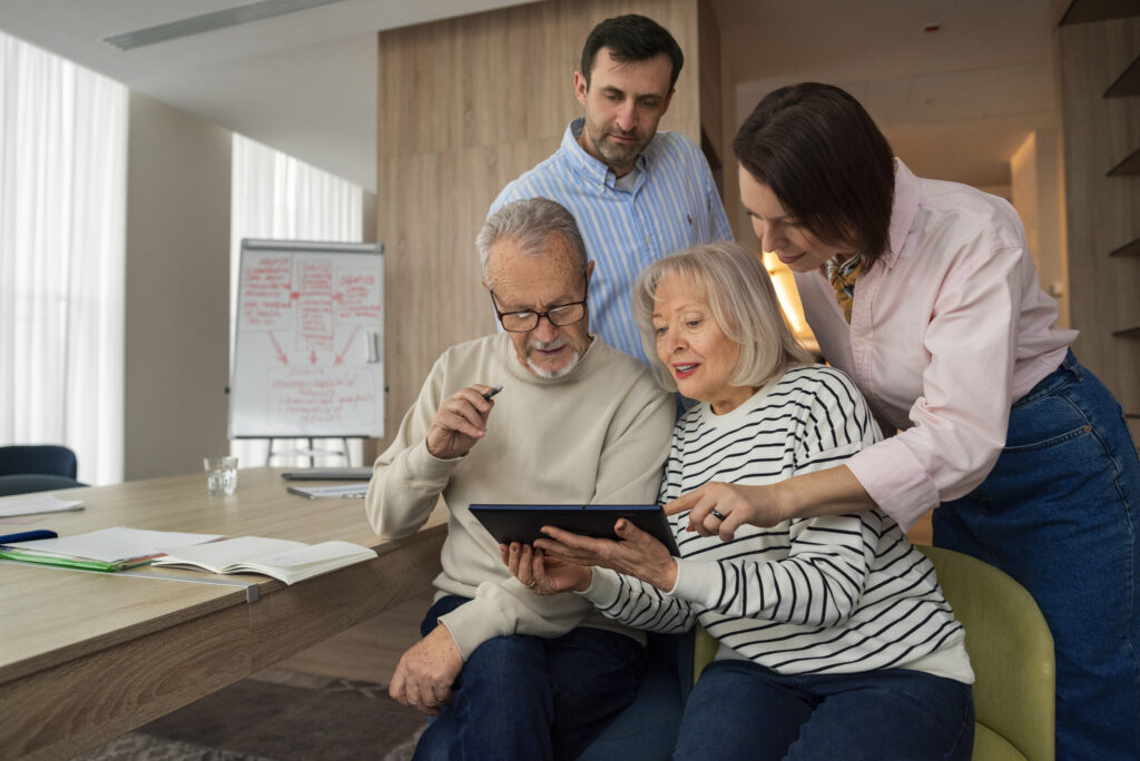 Older couple reviewing information on a tablet with caregivers, illustrating assisted living guidance and family support.