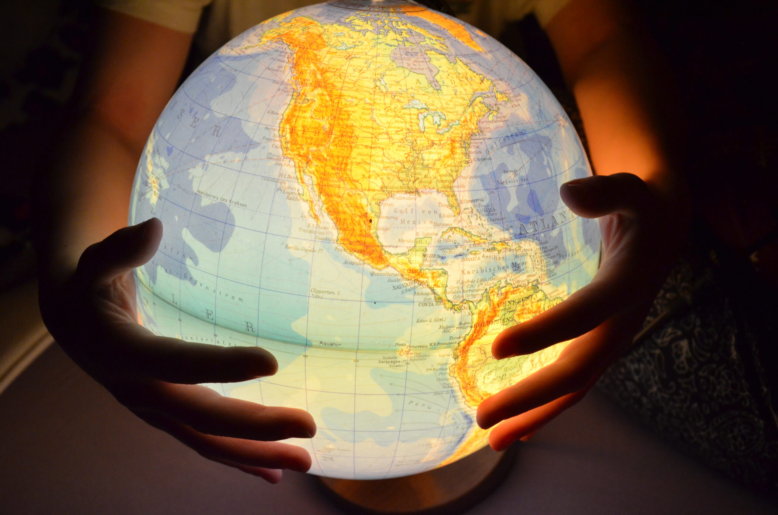 Hands holding an illuminated globe highlighting North America, symbolizing global expansion and market entry into the United States and Canada.