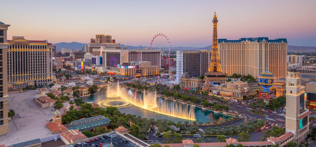 Las Vegas Strip skyline at sunset featuring the Bellagio fountains and Paris Las Vegas Eiffel Tower.