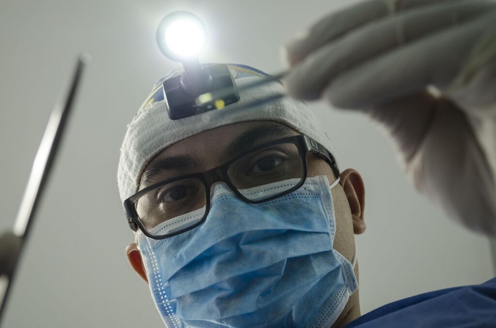 Dentist wearing a mask and headlamp performing a dental examination with tools.