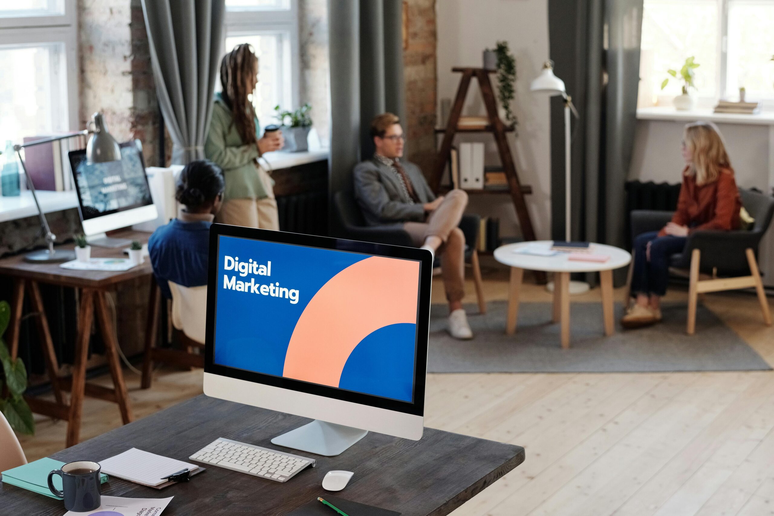 Digital marketing team meeting in a modern office with desktop screen displaying marketing strategy