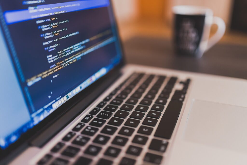 Close-up of a laptop displaying computer code, with a blurred coffee mug in the background.