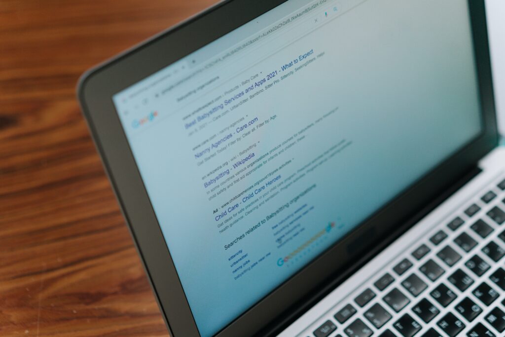 Laptop displaying Google search results for babysitting services and agencies.