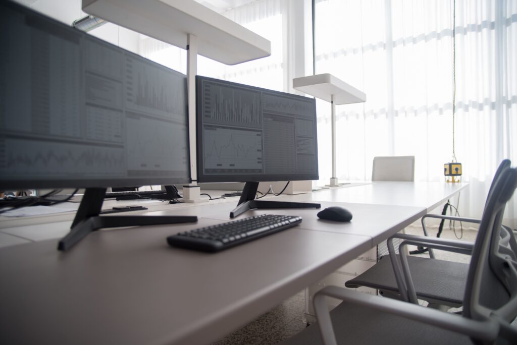 Modern office workspace with multiple monitors displaying data charts and analytics.