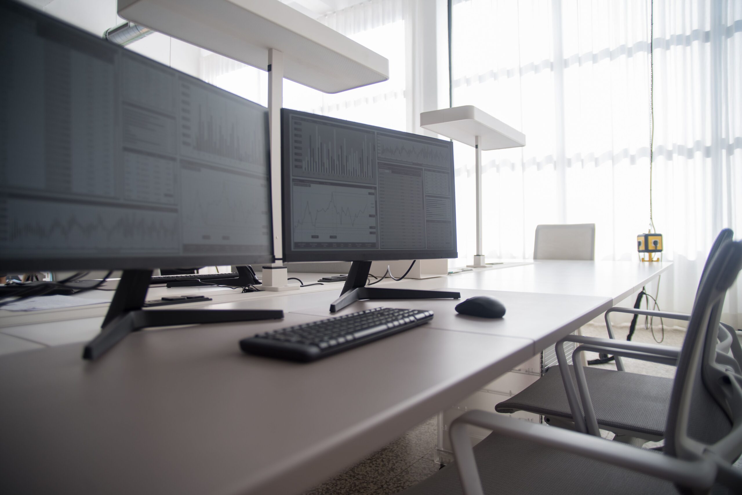 Modern office workspace with multiple monitors displaying data charts and analytics.