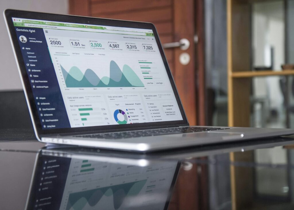 Laptop on a glass desk showing business data on screen